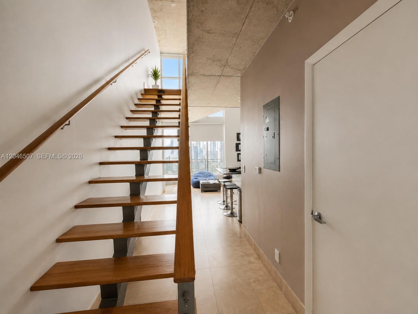 A staircase with wooden treads and a metal frame leads toward a bright living area — 690 SW 1st Ct # 3104, Miami FL 33130, MIAMI, FL