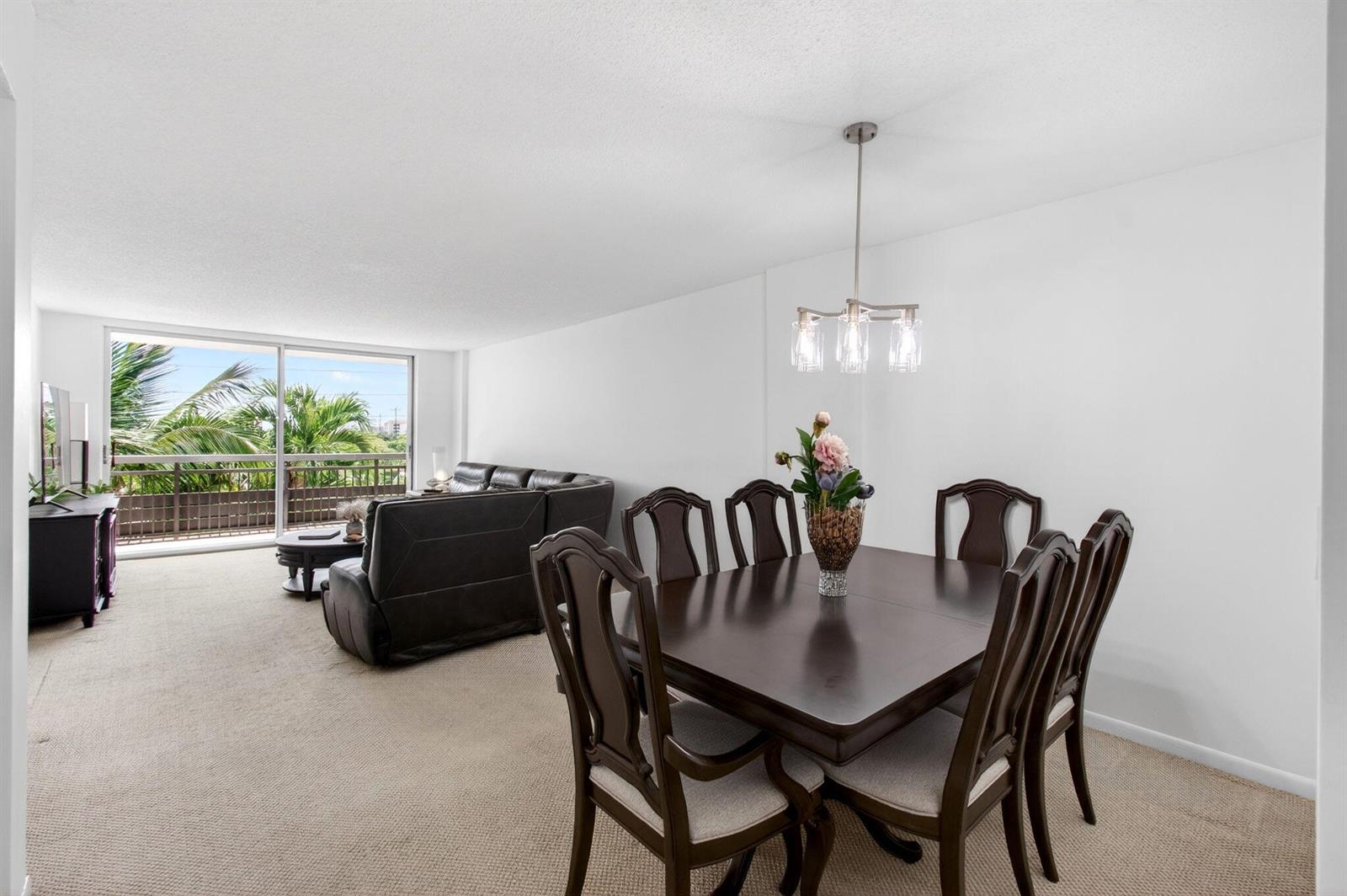 A dining area with a dark wood table and chairs sits beside a living room — 555 NW 4 Avenue # 4230, Boca Raton FL 33432, BOCA RATON, FL