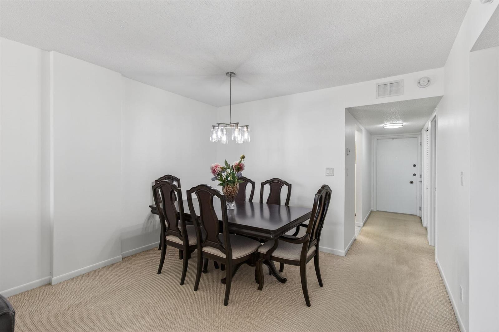 A dining room features a dark wood table with six chairs under a modern chandelier — 555 NW 4 Avenue # 4230, Boca Raton FL 33432, BOCA RATON, FL