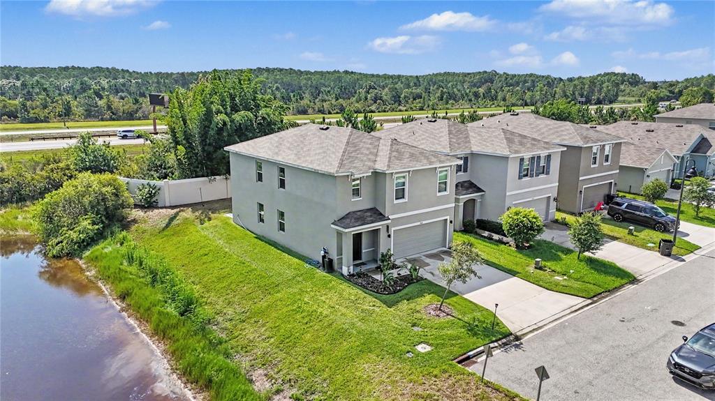 An aerial view shows a two-story suburban house with a garage next to a pond — 3446 SUNCOAST PLAINS DRIVE, ODESSA, FL