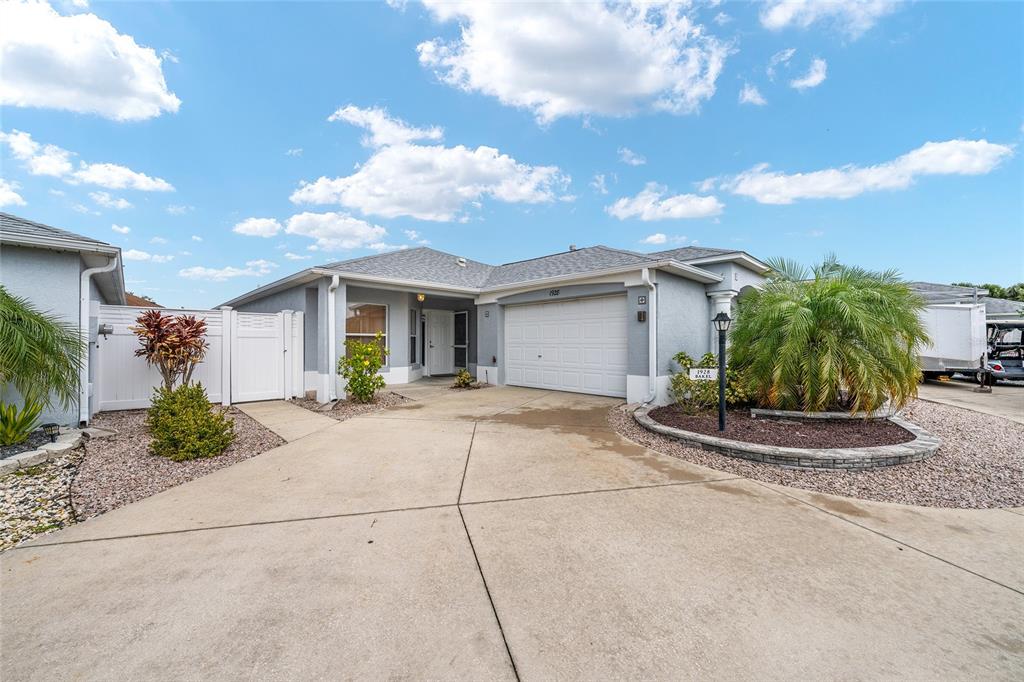 A single-story house with a concrete driveway, a two-car garage, and a palm tree — 1928 PEACHTREE AVENUE, THE VILLAGES, FL