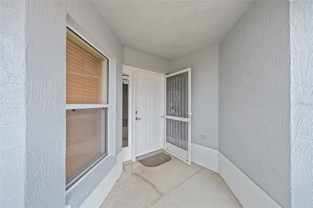 A covered entryway features a white front door with a screen door and a window — 1928 PEACHTREE AVENUE, THE VILLAGES, FL