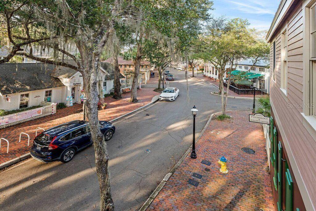 An elevated view of a brick-paved street lined with shops, trees, and parked cars — 5341 SW 91ST TERRACE UNIT 201, GAINESVILLE, FL