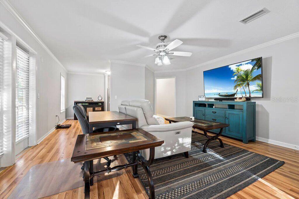 A living room features a light-colored sofa, a blue media console, and wood flooring — 5341 SW 91ST TERRACE UNIT 201, GAINESVILLE, FL