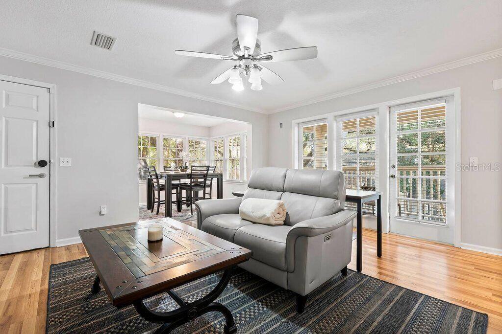 A living room features a gray sofa, a wooden coffee table, and a dining area beyond — 5341 SW 91ST TERRACE UNIT 201, GAINESVILLE, FL