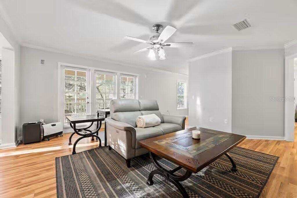 A living room features a gray loveseat, a wooden coffee table, and hardwood flooring — 5341 SW 91ST TERRACE UNIT 201, GAINESVILLE, FL