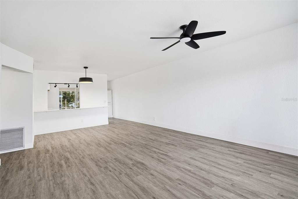 An empty living room features light gray wood-look flooring, white walls, and a ceiling fan — 2431 CANADIAN WAY UNIT 47, CLEARWATER, FL