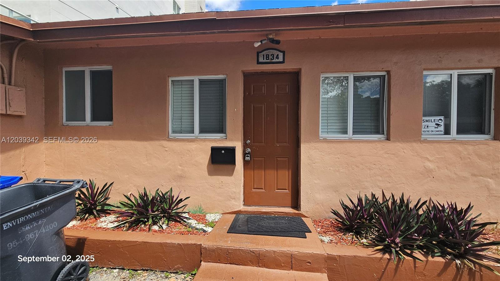 The exterior of a single-story building features a brown door, windows, and landscaping — 1830 Monroe St # 1834, Hollywood FL 33020, HOLLYWOOD, FL