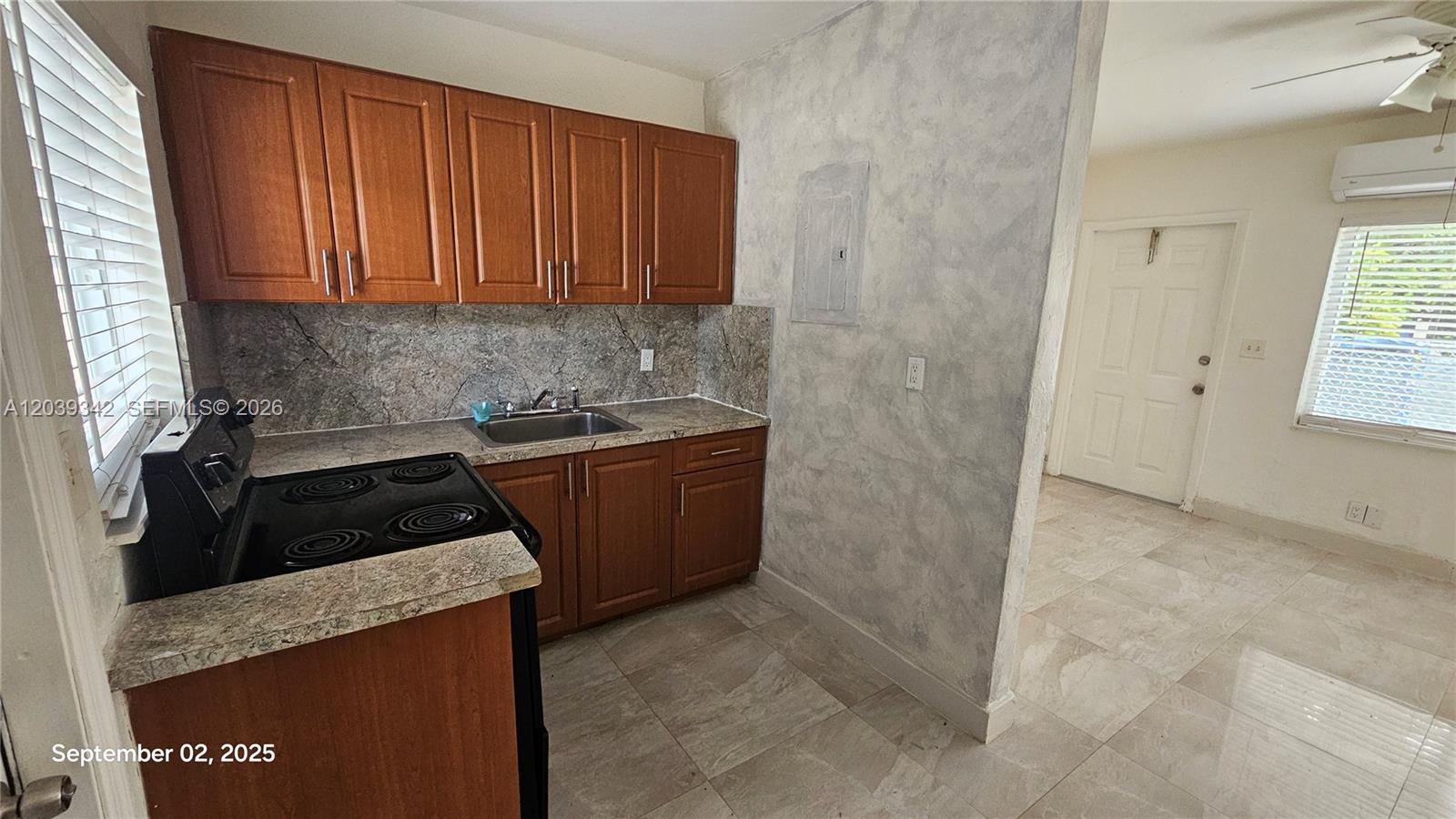 A small kitchen features wooden cabinets, a black electric stove, and a stone-patterned backsplash — 1830 Monroe St # 1834, Hollywood FL 33020, HOLLYWOOD, FL