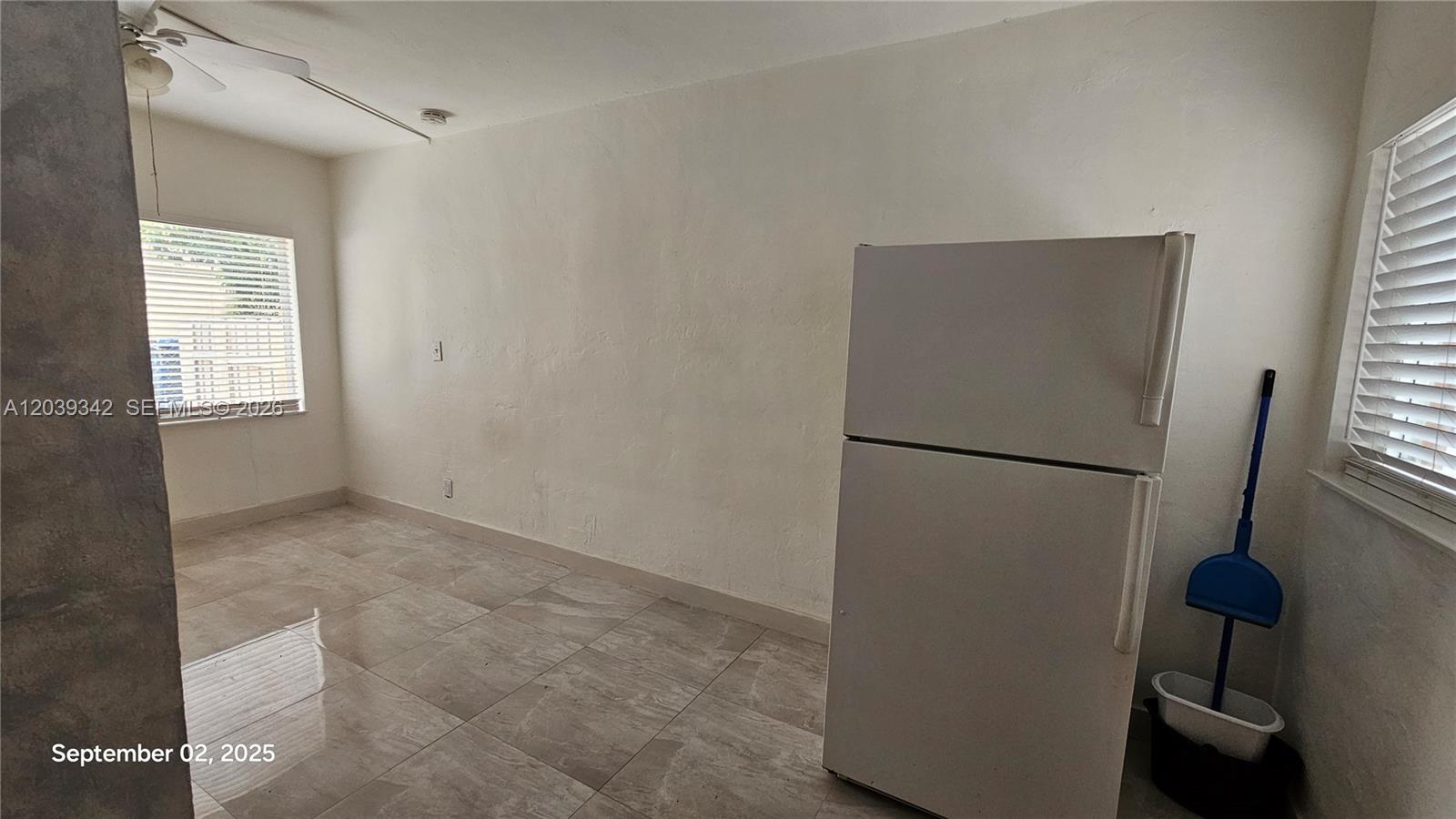 A room with tiled floors, white walls, a white refrigerator, and a blue dustpan — 1830 Monroe St # 1834, Hollywood FL 33020, HOLLYWOOD, FL