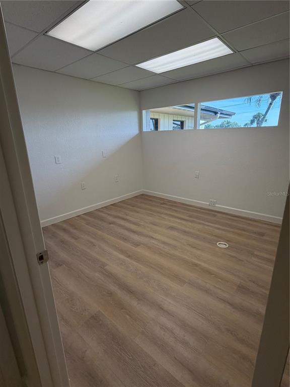 An empty office room features light wood-look flooring, white walls, and horizontal clerestory windows — 3443 TAMIAMI TRAIL UNIT C, PORT CHARLOTTE, FL