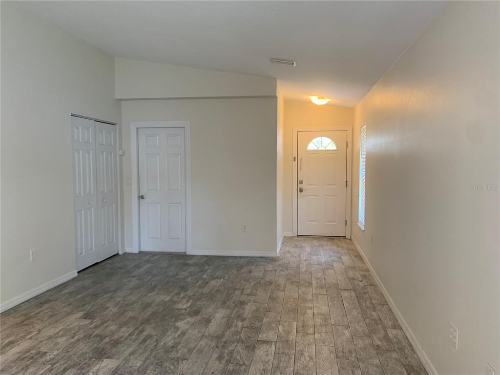 An entryway features wood-look tile flooring, a white front door, and two interior doors — 1875 VAMO DRIVE, SARASOTA, FL