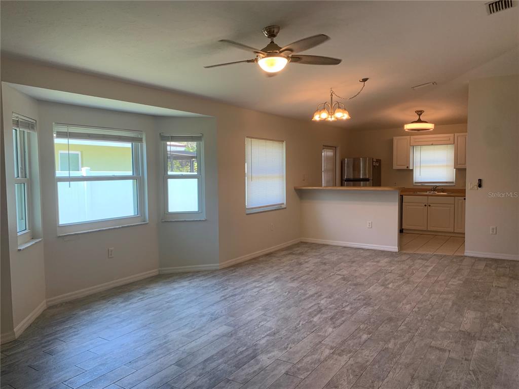 A living room with wood-look tile flooring opens to a kitchen with a breakfast bar — 1875 VAMO DRIVE, SARASOTA, FL