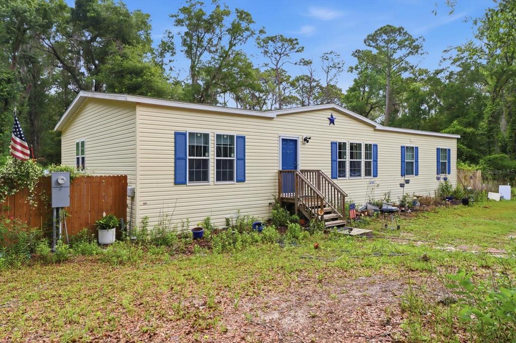 A single-story, light yellow manufactured home with blue shutters and a wooden front porch — 3883 SW 165TH AVENUE ROAD, OCALA, FL