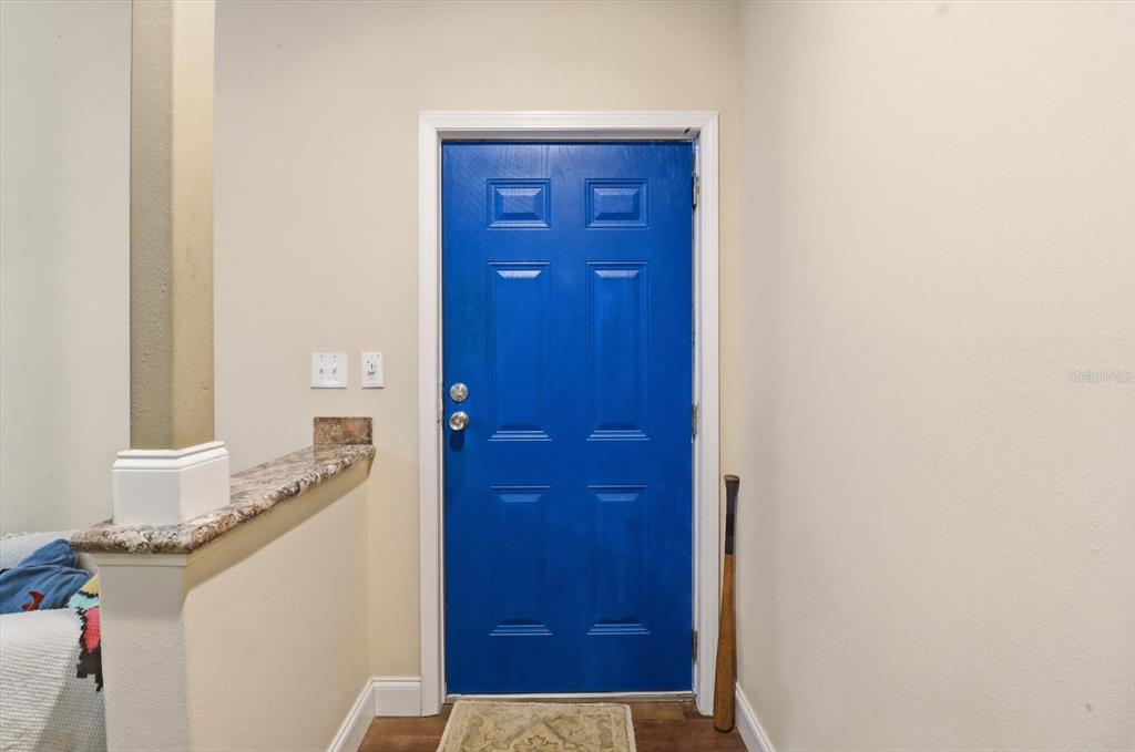 A bright blue front door is situated in a neutral-walled entryway with a baseball bat — 3883 SW 165TH AVENUE ROAD, OCALA, FL