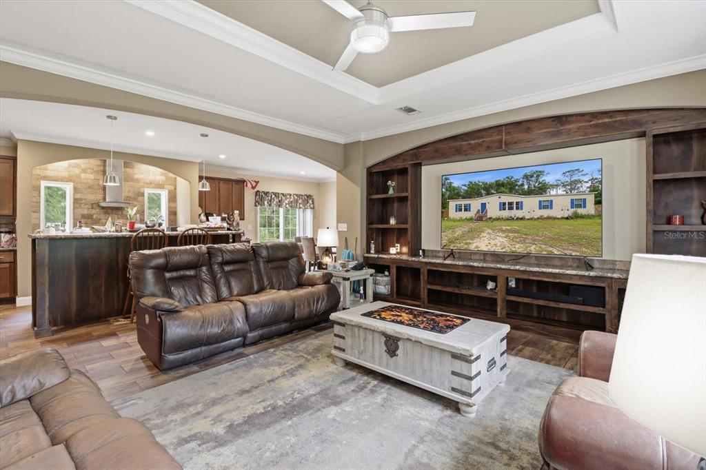 A living room features a large television, built-in wooden shelving, and a leather sofa — 3883 SW 165TH AVENUE ROAD, OCALA, FL