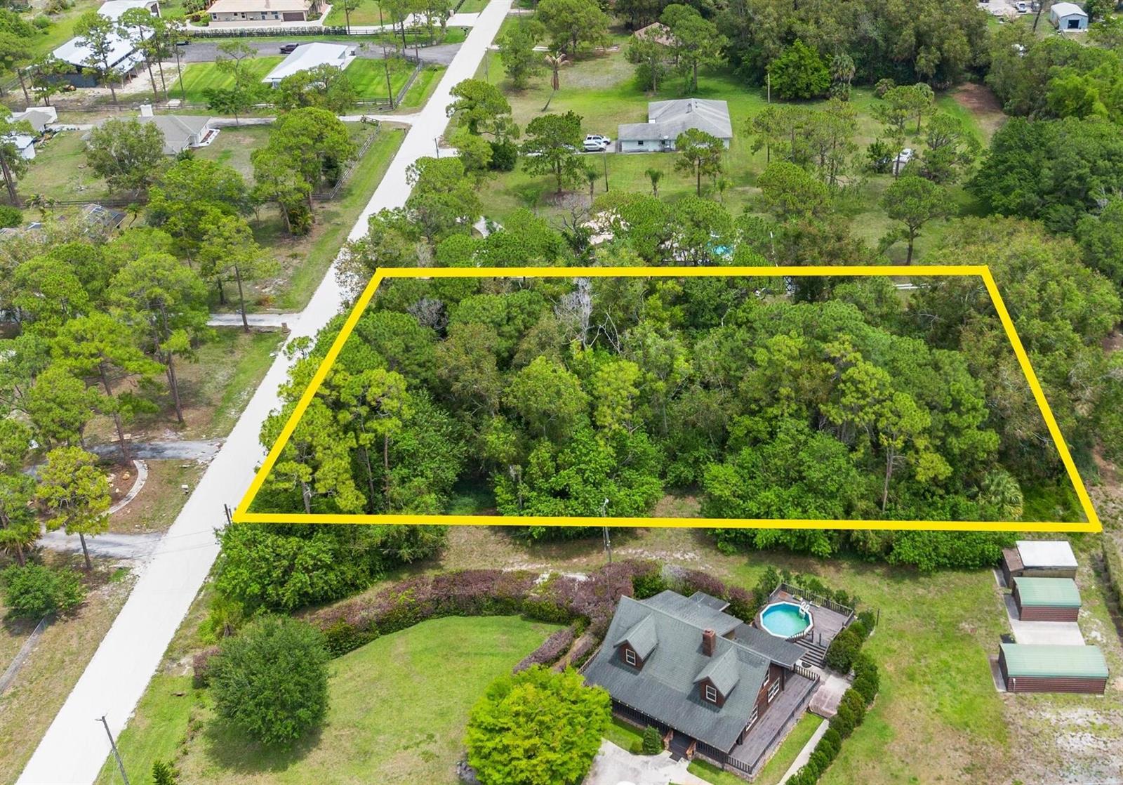 An aerial view shows a rectangular wooded lot outlined in yellow next to a house — Tbd 122nd Drive N, FL 33411, FL