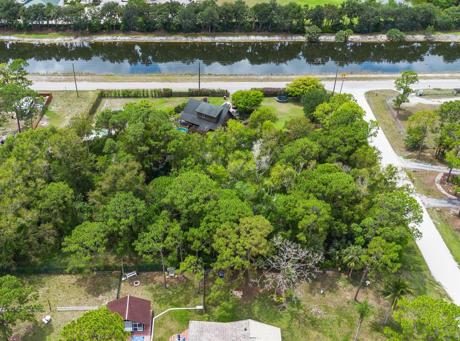 An aerial view shows a house surrounded by dense trees next to a canal — Tbd 122nd Drive N, FL 33411, FL