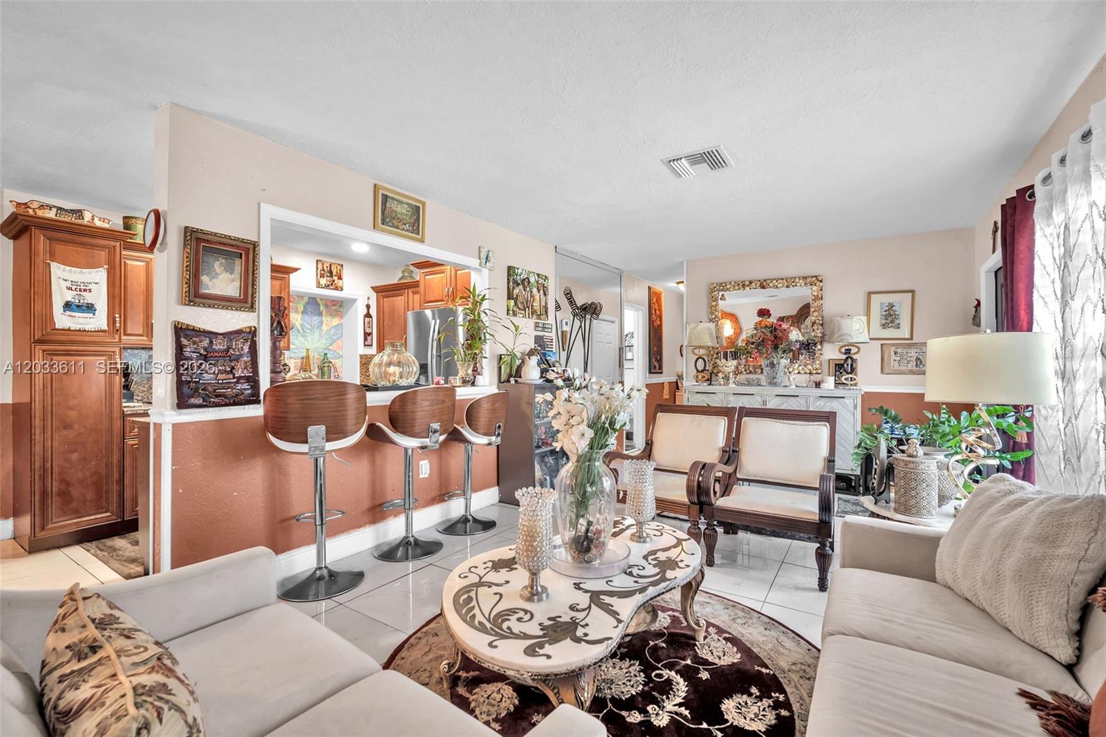 A living room features a breakfast bar with three stools, tile flooring, and neutral furniture — 3391 NW 8th St, Lauderhill FL 33311, LAUDERHILL, FL