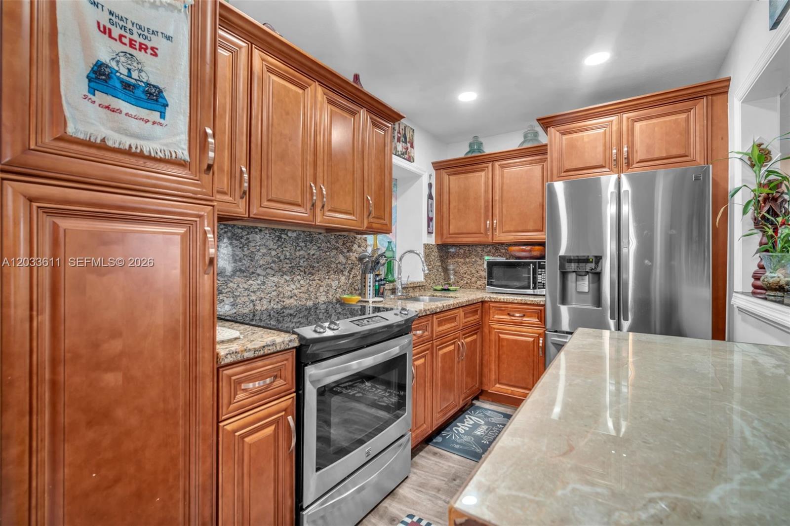 A kitchen features wood cabinets, granite countertops, stainless steel appliances, and a central island — 3391 NW 8th St, Lauderhill FL 33311, LAUDERHILL, FL
