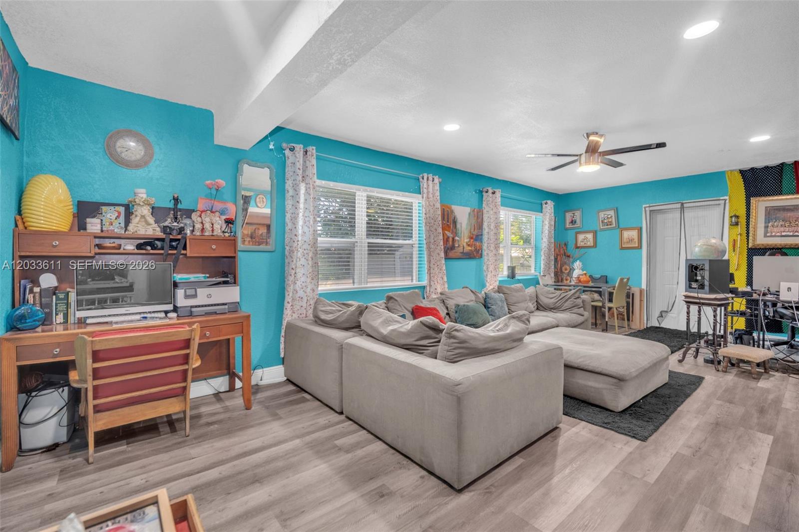 A living room with bright blue walls, a large gray sectional sofa, and a desk — 3391 NW 8th St, Lauderhill FL 33311, LAUDERHILL, FL