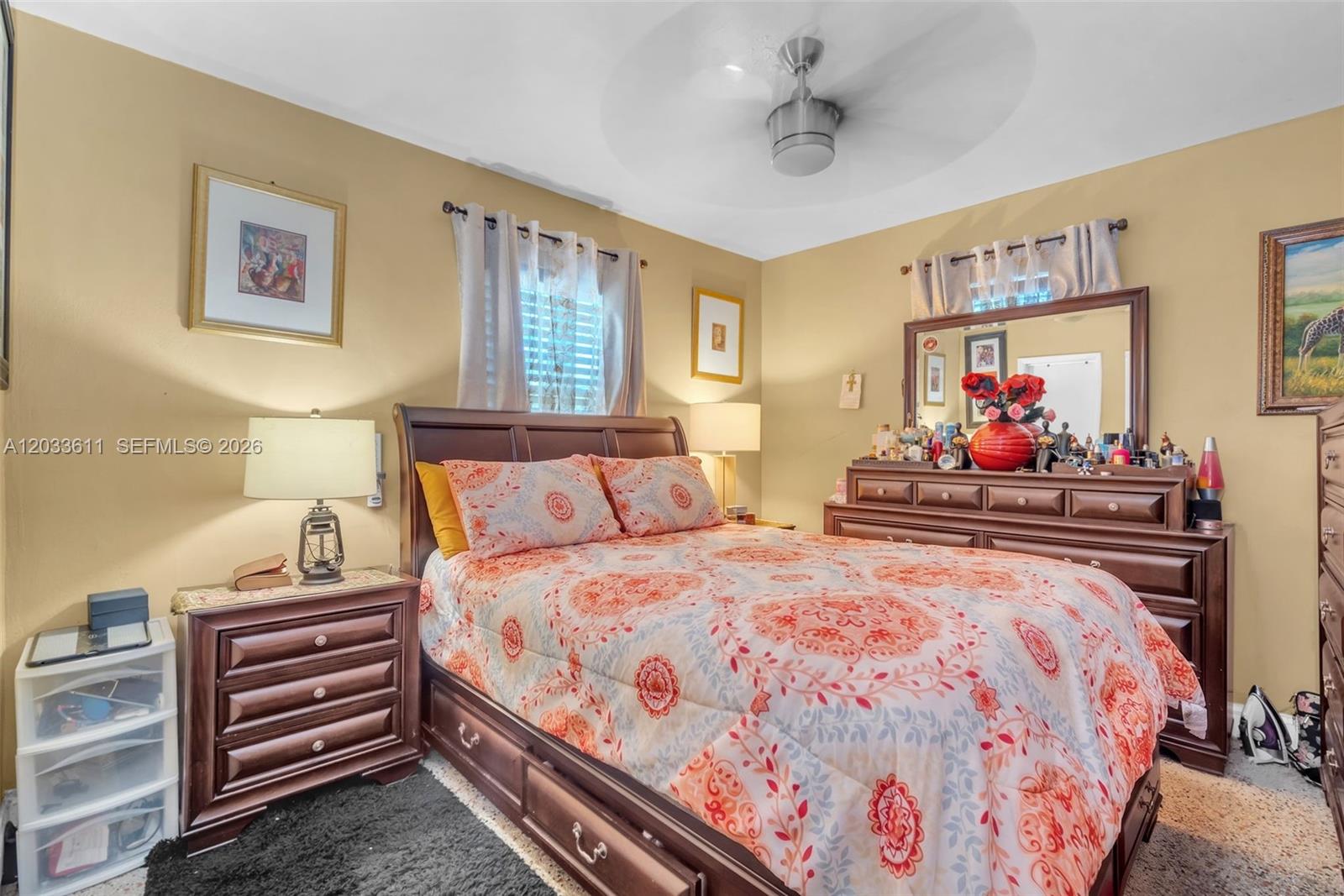 A bedroom features a wooden bed frame, a matching dresser with a mirror, and tan walls — 3391 NW 8th St, Lauderhill FL 33311, LAUDERHILL, FL