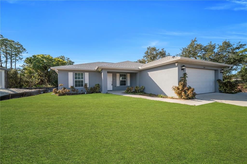 A single-story gray house with a white garage door and a large front lawn — 2617 53RD ST W, LEHIGH ACRES, FL