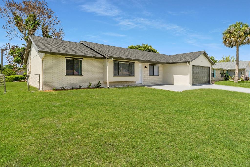 A single-story house with a brick facade, gray roof, and attached garage sits on grass — 940 FOREST STREET NE, PALM BAY, FL