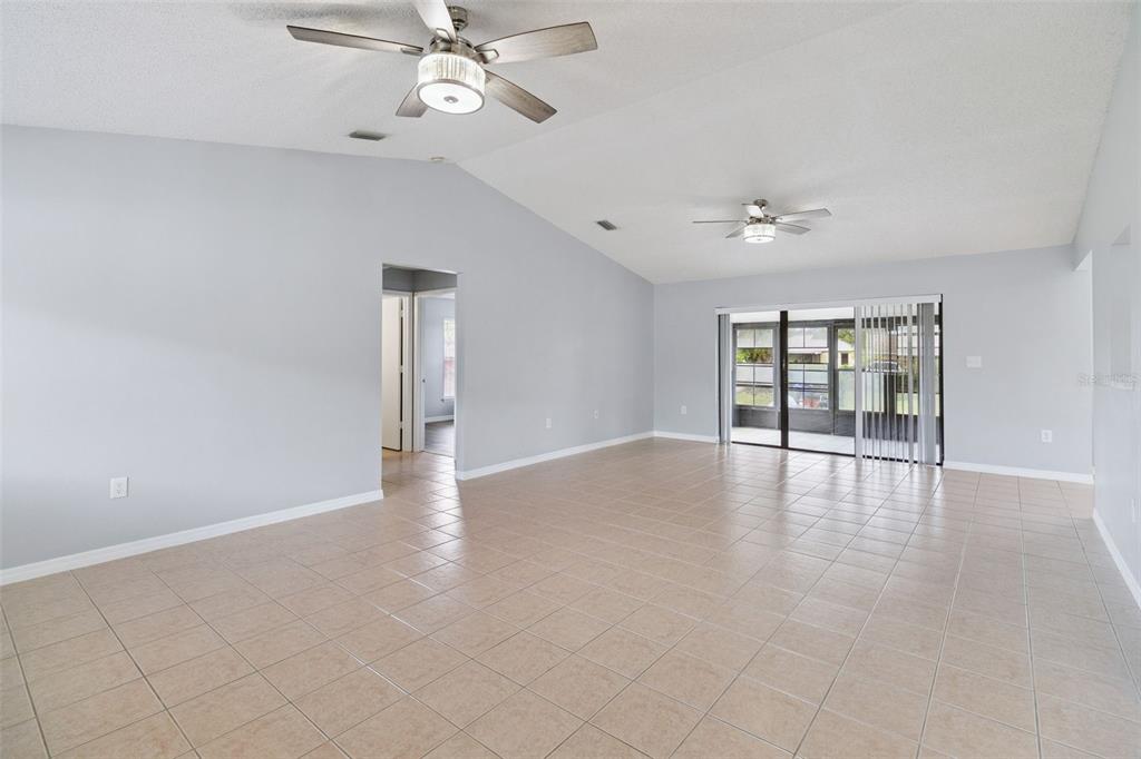 A spacious living room features light gray walls, tiled flooring, and two ceiling fans — 940 FOREST STREET NE, PALM BAY, FL