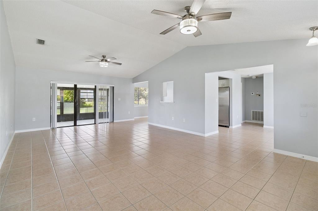 An open-concept living area features light gray walls, tiled floors, and two ceiling fans — 940 FOREST STREET NE, PALM BAY, FL