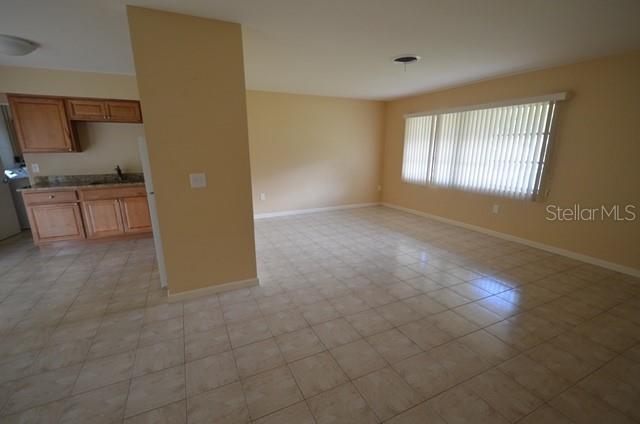 An open-concept living area with light-colored tile flooring and a kitchen with wood cabinets — 612 SHAMROCK BOULEVARD, VENICE, FL