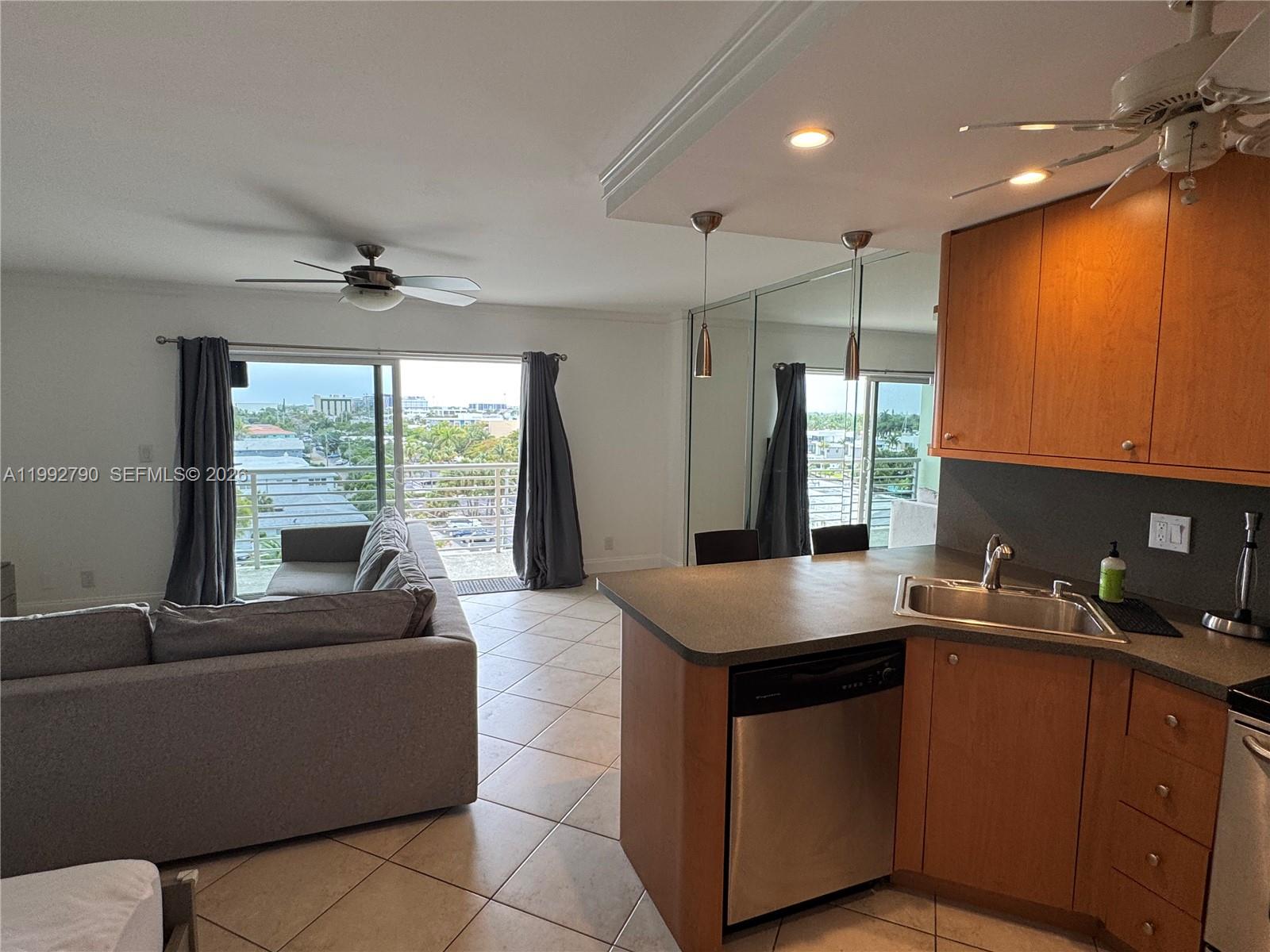 A kitchen with wood cabinets, stainless steel appliances, and a balcony view of the outdoors — FORT LAUDERDALE, FL