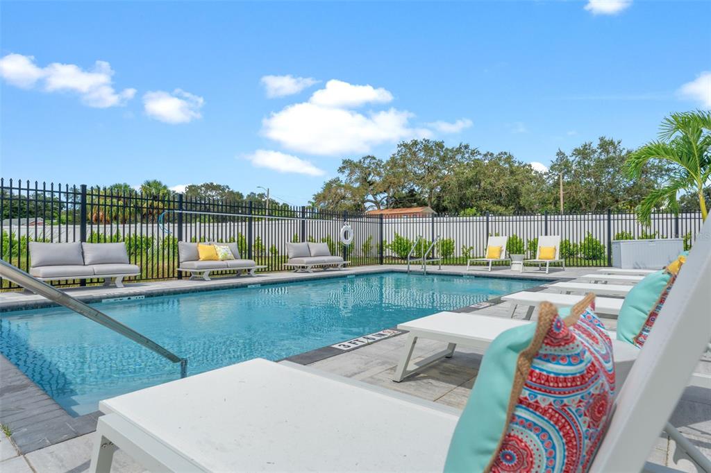 An outdoor swimming pool surrounded by lounge chairs and a black metal fence — 6222 64TH WAY N, PINELLAS PARK, FL
