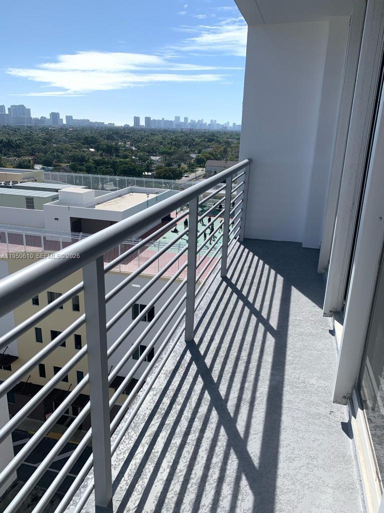 A high-rise balcony with a metal railing overlooks a suburban landscape and distant city skyline — 1720 Harrison St # 9A, Hollywood FL 33020, HOLLYWOOD, FL