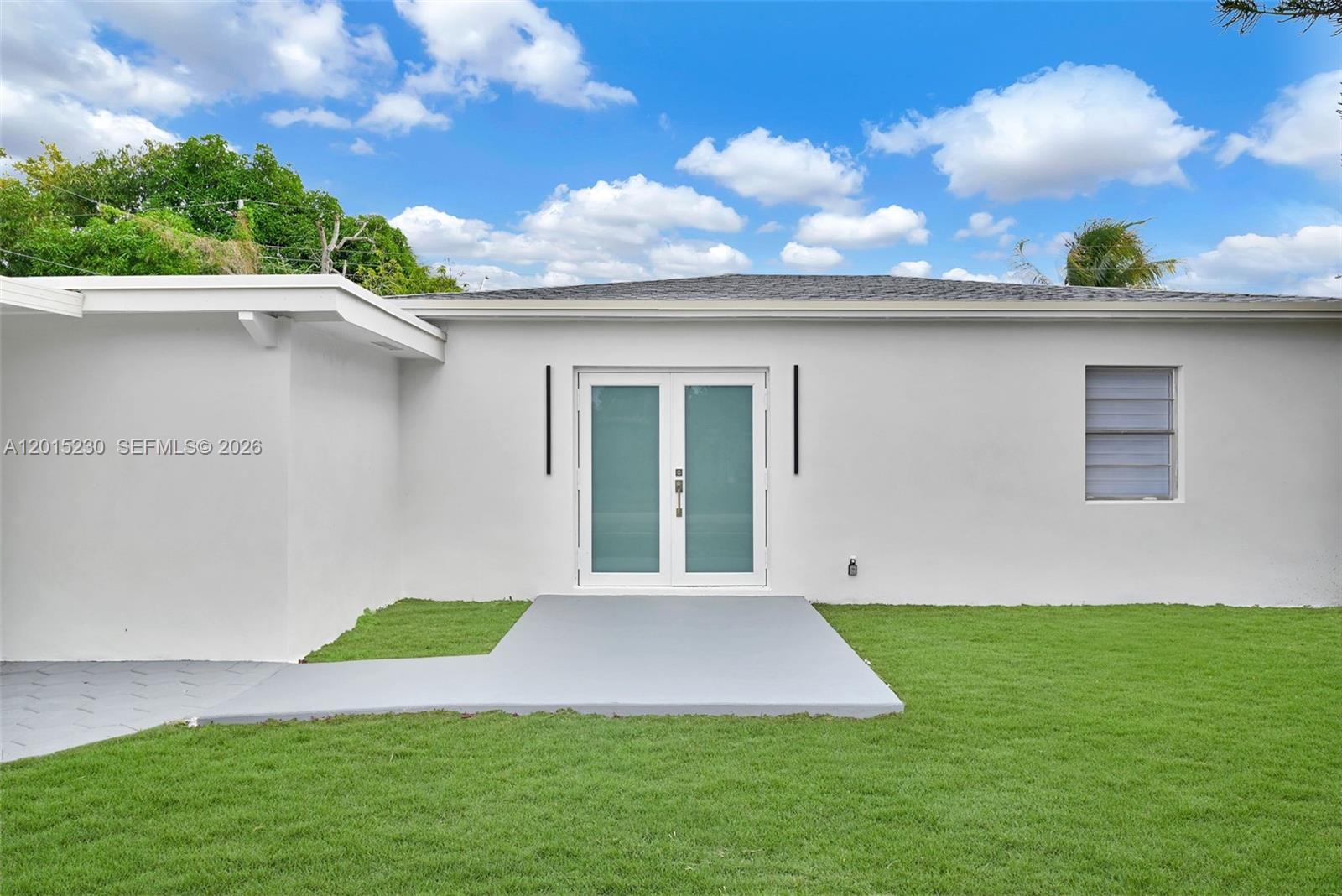 A white house features a covered carport with a gray hexagonal-patterned concrete driveway — 12621 NW 22nd Ct, Miami FL 33167, MIAMI, FL
