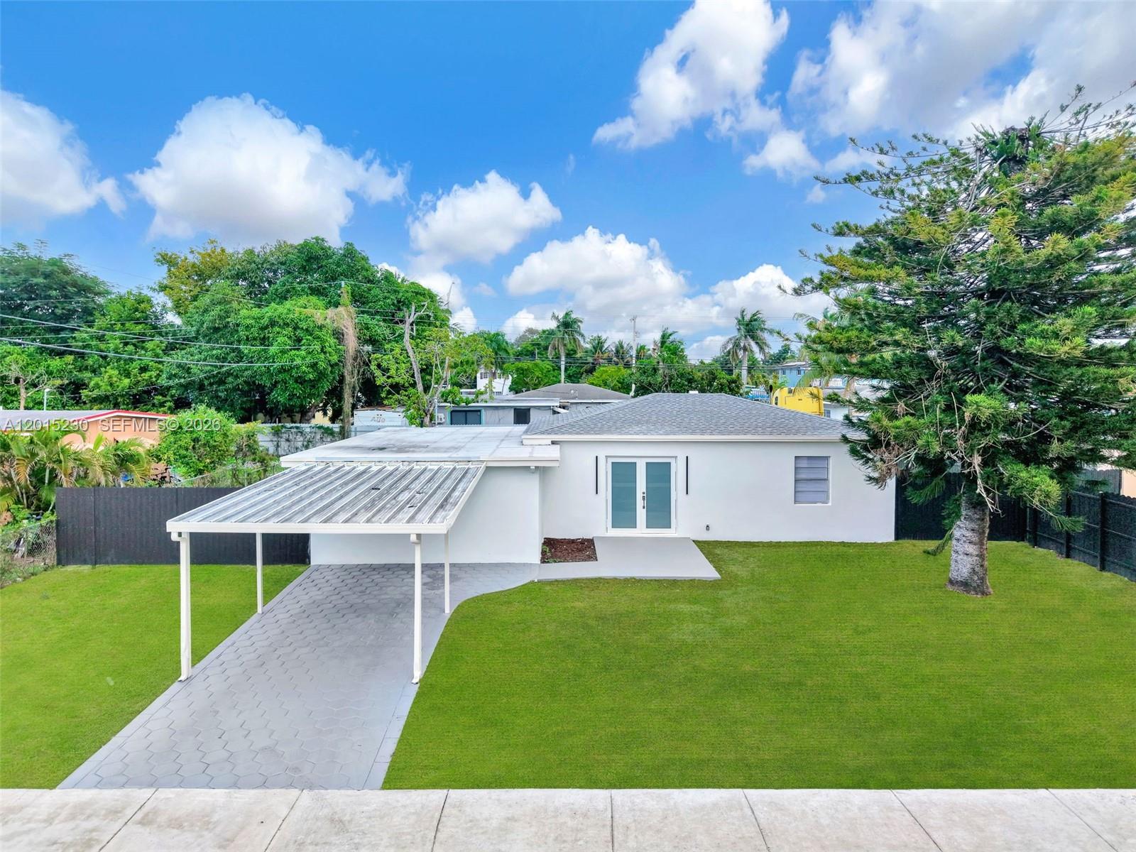 A single-story house with a carport and a black fence sits on a grassy lot — 12621 NW 22nd Ct, Miami FL 33167, MIAMI, FL