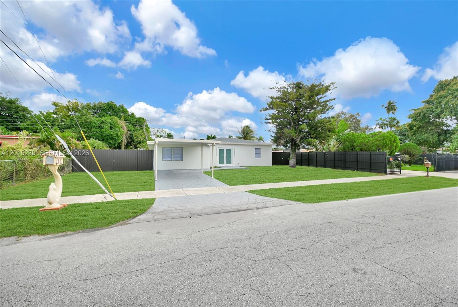 A white single-story house features a metal carport, a paved driveway, and a large lawn — 12621 NW 22nd Ct, Miami FL 33167, MIAMI, FL