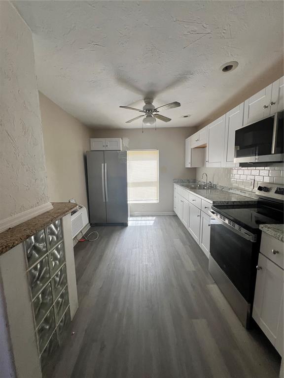 A galley kitchen features white cabinets, stainless steel appliances, and light wood-look flooring — 408 HENRY BUTTS DRIVE, DAYTONA BEACH, FL