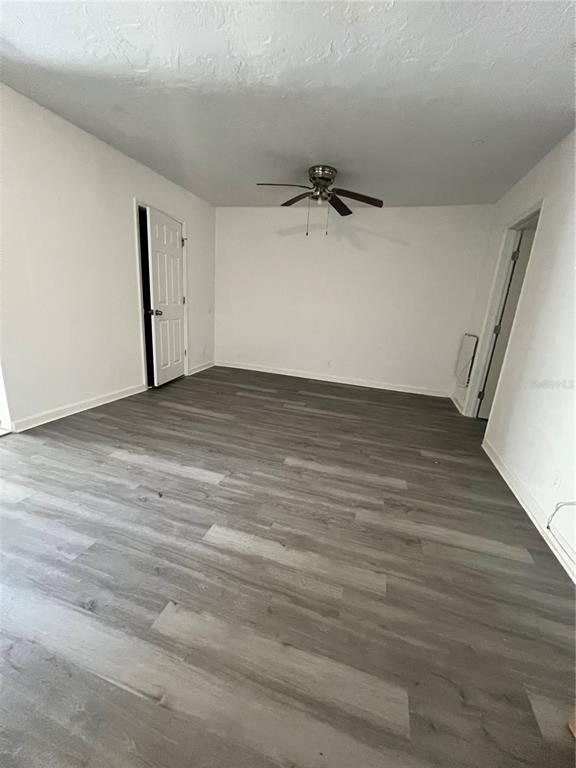 An empty room features gray wood-look flooring, white walls, and a ceiling fan — 408 HENRY BUTTS DRIVE, DAYTONA BEACH, FL