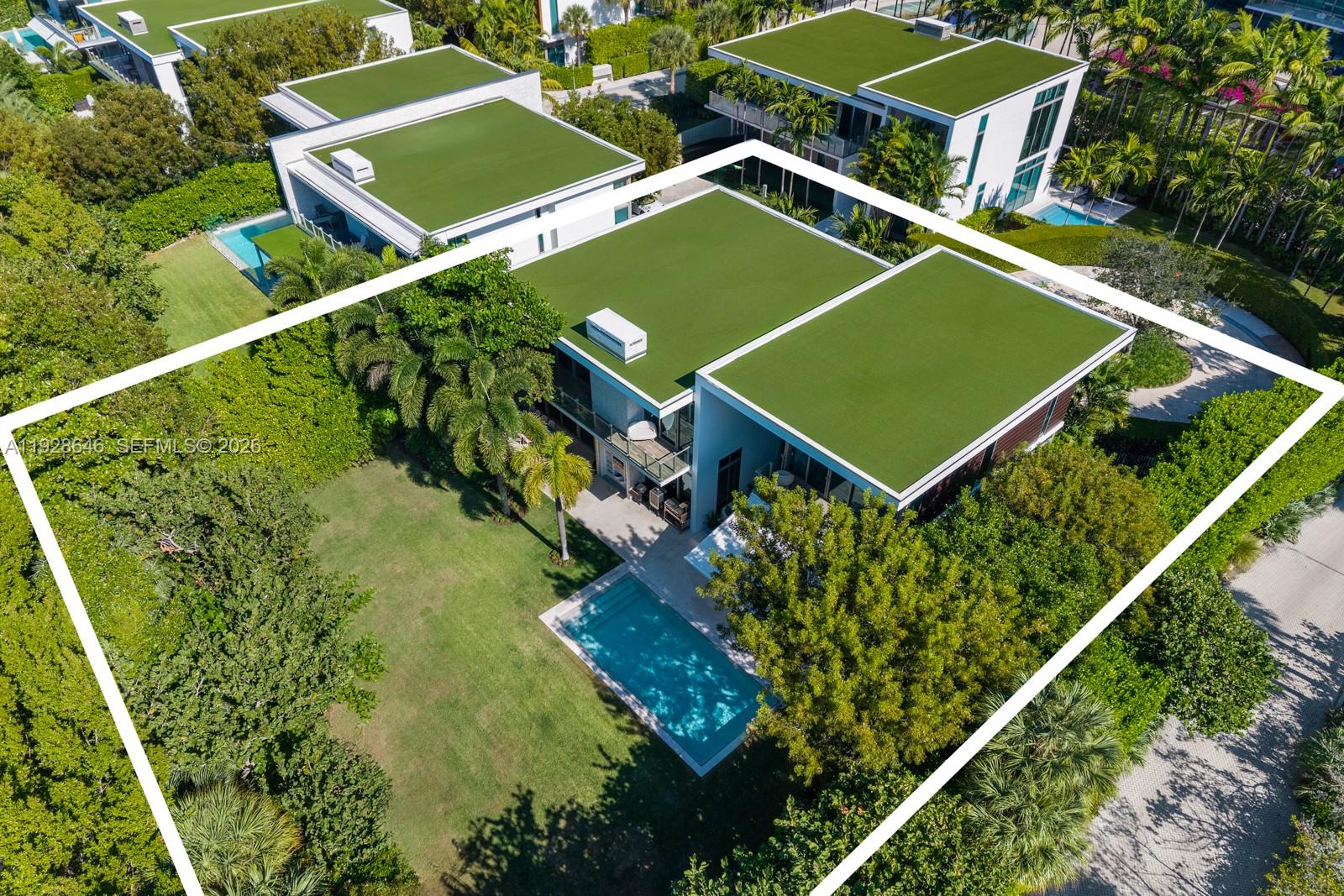 An aerial view shows a modern house with a green roof, swimming pool, and yard — 111 Reef Ln, Key Biscayne FL 33149, KEY BISCAYNE, FL