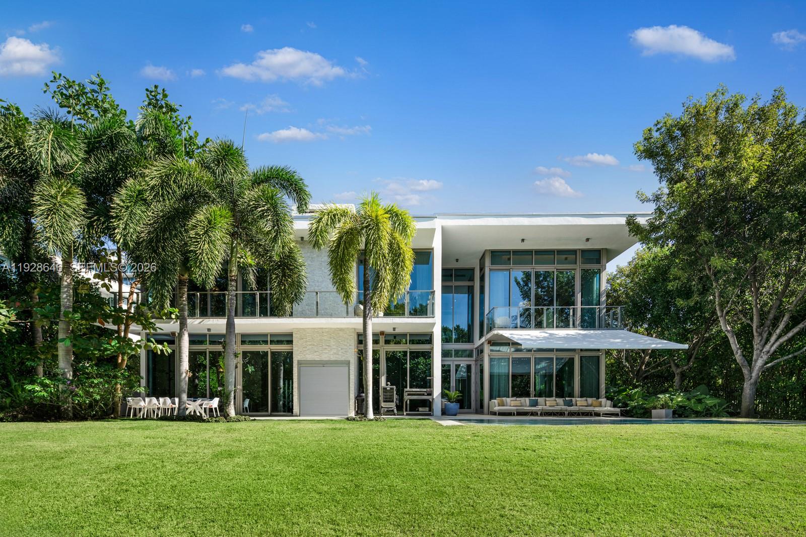 A modern two-story house with floor-to-ceiling windows, a large lawn, and surrounding palm trees — 111 Reef Ln, Key Biscayne FL 33149, KEY BISCAYNE, FL
