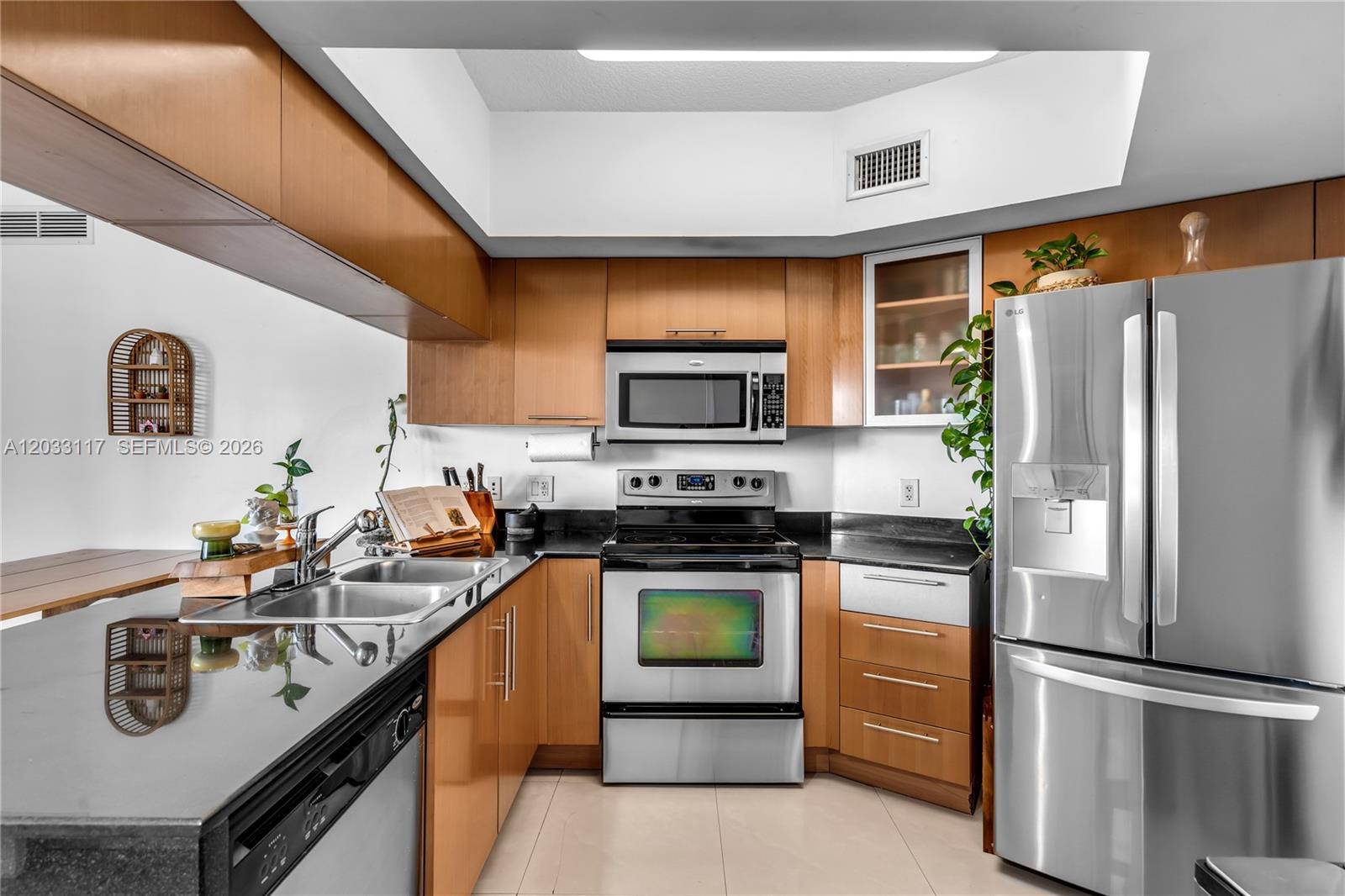 A kitchen features wood cabinets, stainless steel appliances, and black countertops — 1750 N Bayshore Dr # 1815, Miami FL 33132, MIAMI, FL