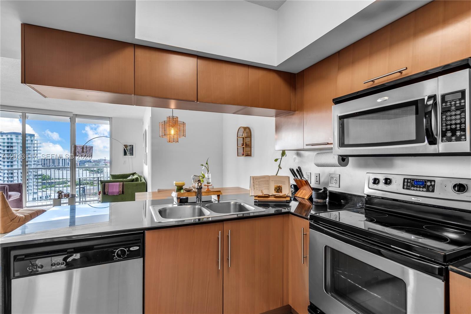 A kitchen features wood cabinets, stainless steel appliances, black countertops, and a view of balconies — 1750 N Bayshore Dr # 1815, Miami FL 33132, MIAMI, FL