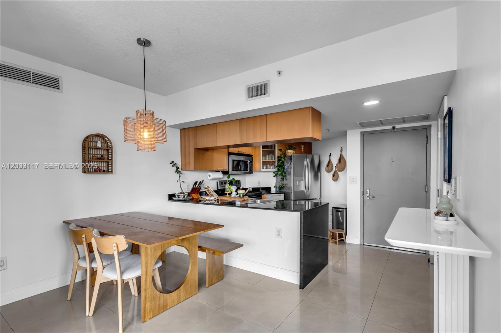 A kitchen with wooden cabinets and black countertops sits next to a dining area — 1750 N Bayshore Dr # 1815, Miami FL 33132, MIAMI, FL