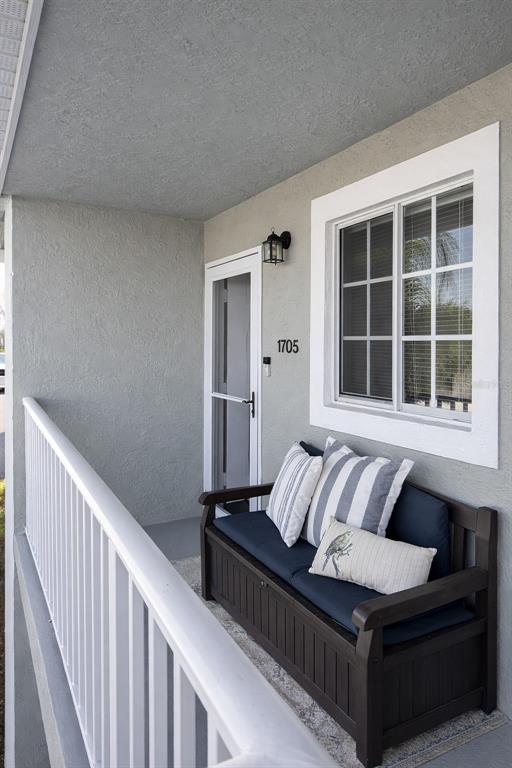A covered balcony features a dark storage bench with cushions and a white railing — 3310 LOVELAND BOULEVARD UNIT 1705, PUNTA GORDA, FL