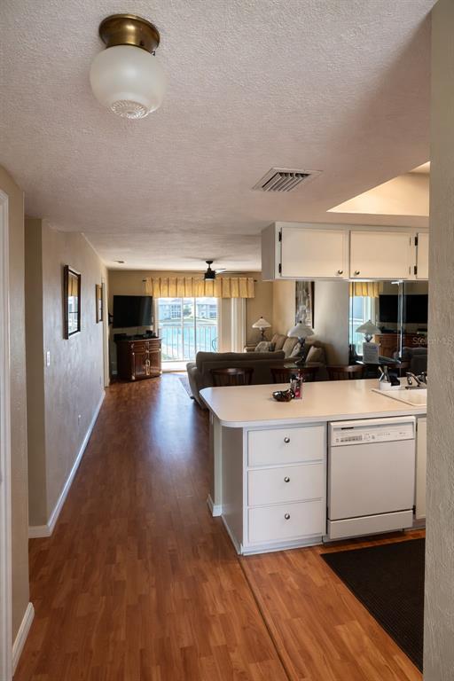 A view from a kitchen looking toward a living room with wood-look flooring and balcony — 3310 LOVELAND BOULEVARD UNIT 1705, PUNTA GORDA, FL