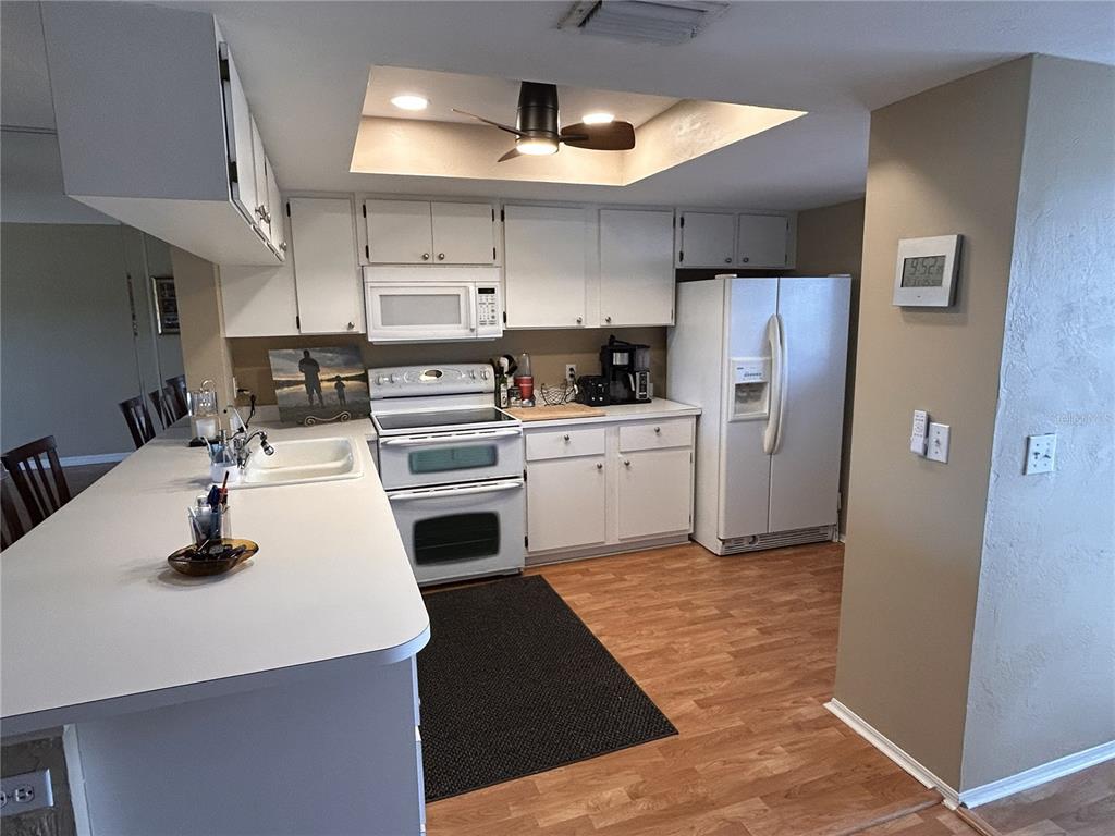 A kitchen features white cabinets, white appliances, a breakfast bar, and wood-look flooring — 3310 LOVELAND BOULEVARD UNIT 1705, PUNTA GORDA, FL
