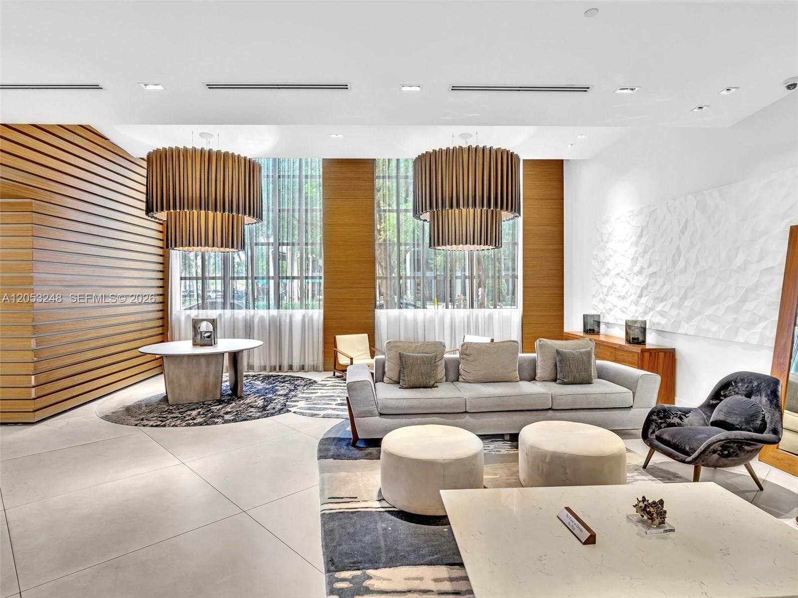 A modern lobby features wood-paneled walls, two large tiered chandeliers, and contemporary lounge furniture — 3301 NE 1st Ave # H2706, Miami FL 33137, MIAMI, FL