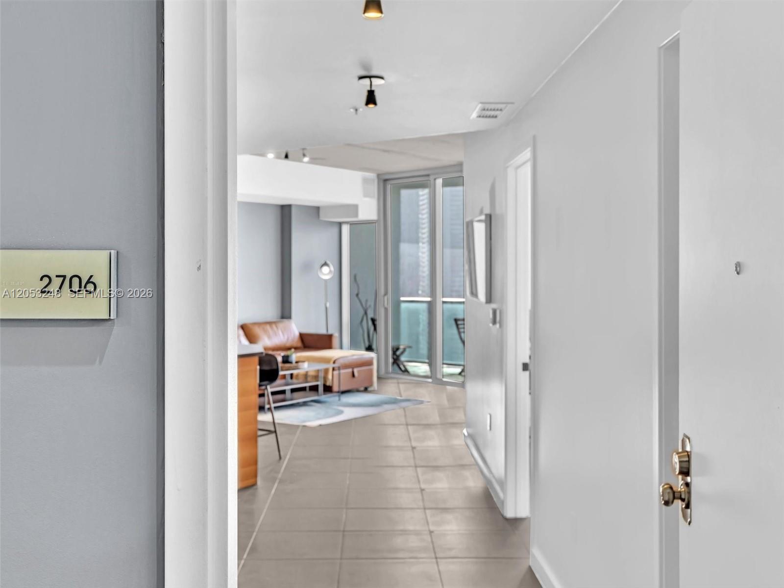 A view from a doorway looks into a living area with tile floors and balcony access — 3301 NE 1st Ave # H2706, Miami FL 33137, MIAMI, FL