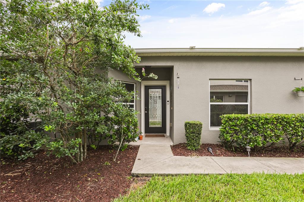 A gray house exterior features a front door with a glass insert and a walkway — 1121 TRAVERTINE TERRACE, SANFORD, FL